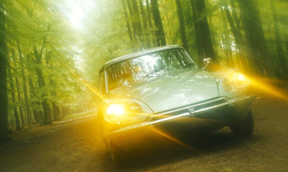 Citroën DS 21 de 1972 de couleur grise en train de rouler vite avec les phares allumés.