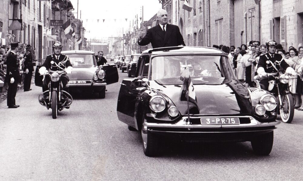 Le Général-de-Gaulle debout dans sa voiture présidentielle noire, lors d'un déplacement à Isles-sur-Suippe dans le département de La Marne le 22 avril 1963.