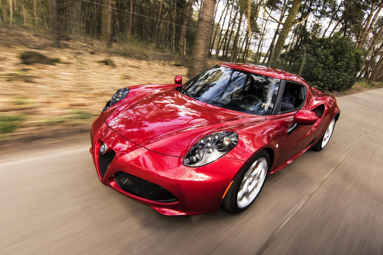 Très belle Alfa Romeo 4C Coupé modèle 2019 de couleur rouge en train de rouler dans une forêt.