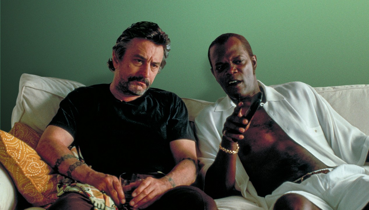 Les acteurs Robert De Niro à gauche et Samuel L. Jackson à droite assis dans un canapé blanc dans le film “Jackie Brown” de Quentin Tarantino et sorti en 1997.