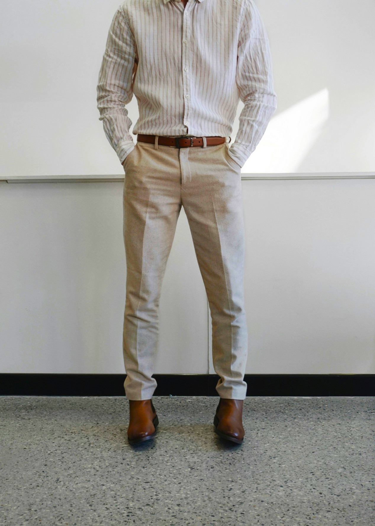 Homme portant une chemise et un pantalon en lin, avec une ceinture en cuir marron foncé et une paire de chaussures en cuir marron.