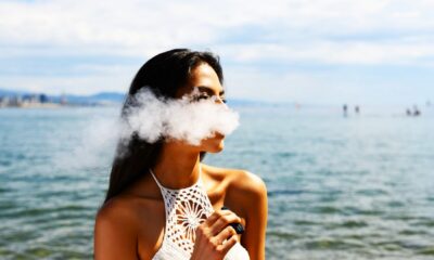 Femme avec un haut blanc sans manches qui fume une cigarette électronique