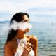 Femme avec un haut blanc sans manches qui fume une cigarette électronique