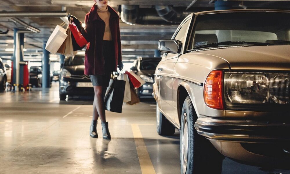 Femme élégante qui revient de son shopping et remonte dans sa voiture vintage, une vieille Mercedes
