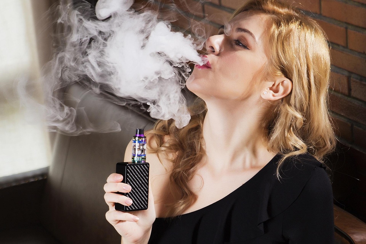 Femme blonde en train de vapoter une cigarette électronique
