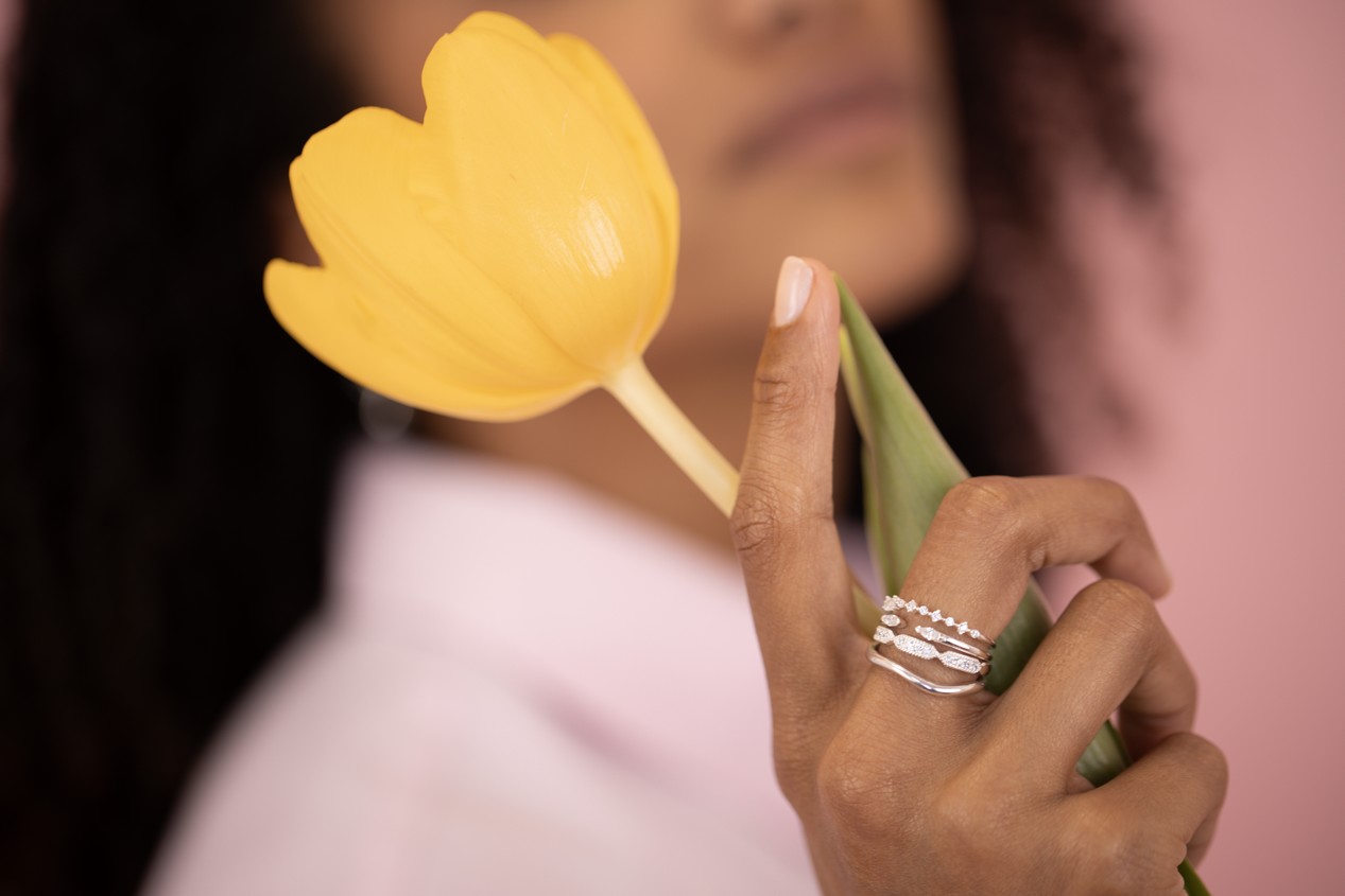Femme tenant une tulipe jaune et portant des bagues