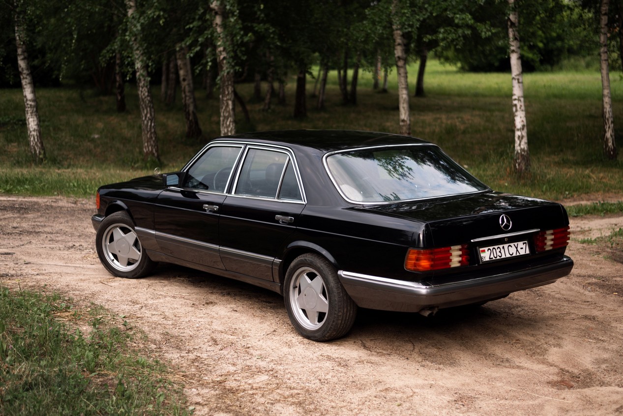 Mercedes Classe S W126 noire garée dans une forêt
