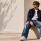 Jeune homme assis qui porte une paire de jeans larges