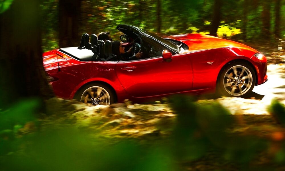 Mazda MX5 cabriolet rouge de 4ème génération modèle 2016 en train de rouler dans une forêt