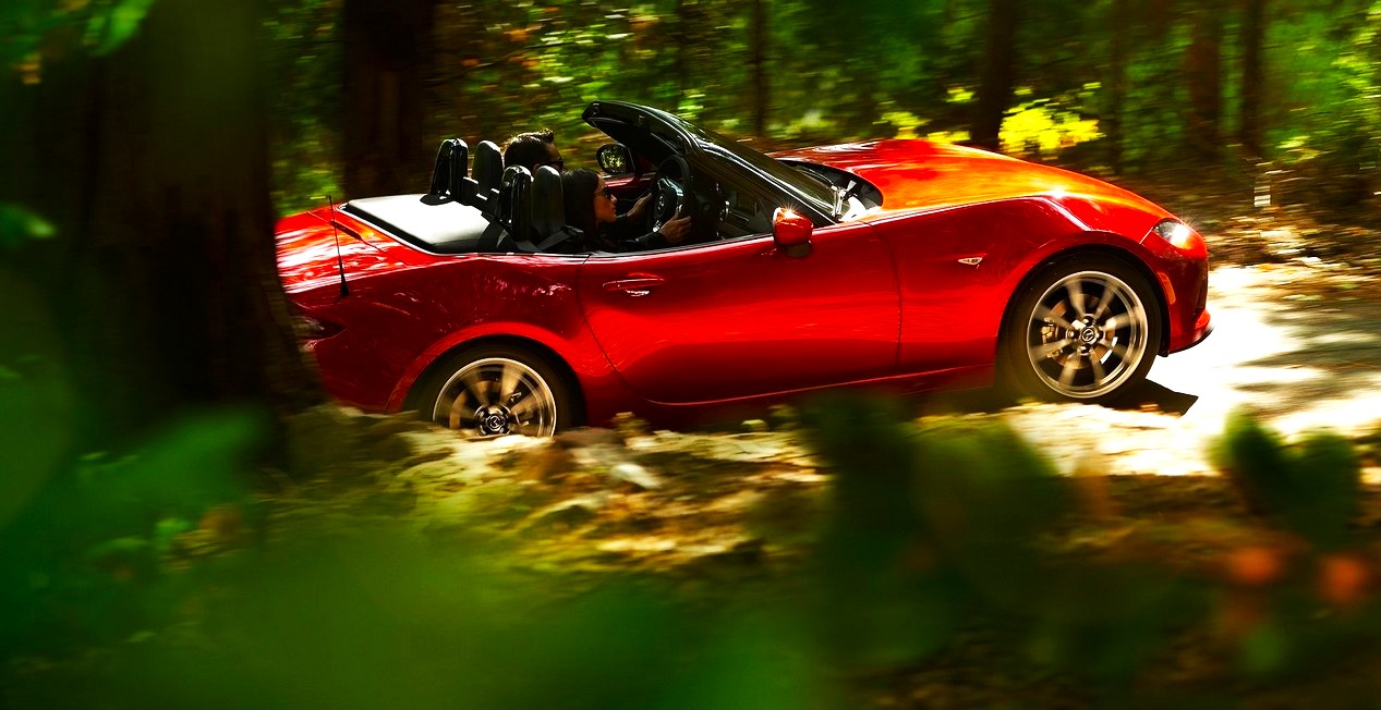 Mazda MX5 cabriolet rouge de 4ème génération modèle 2016 en train de rouler dans une forêt