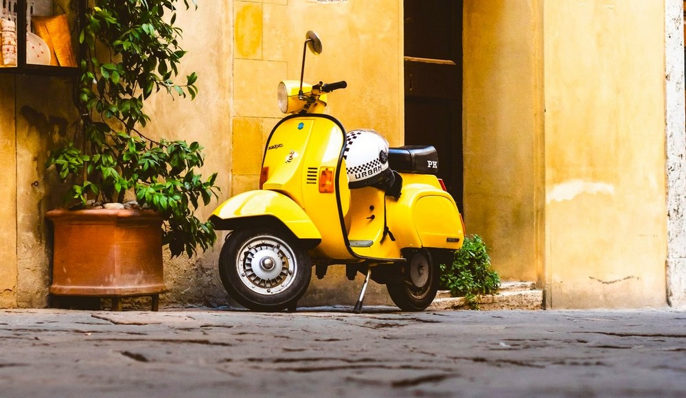 Scooter vintage jaune citron Vespa de Piaggio garée dans une rue